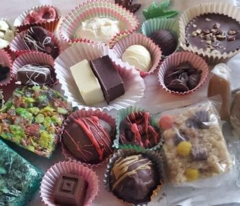 An assortment of colorful homemade chocolates and sweets displayed in paper cups on a tray.